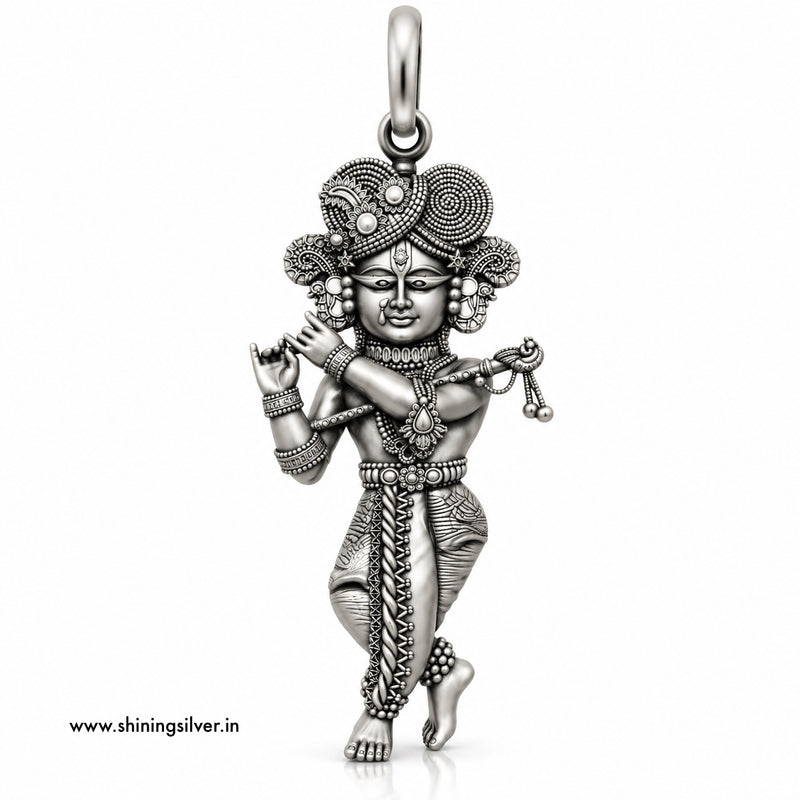 An intricate sterling silver pendant of a dancing Hindu deity, likely Lord Krishna, featuring detailed engravings, textured patterns, and a decorative headdress, shown on a plain white background with a website watermark.