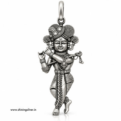 An intricate sterling silver pendant of a dancing Hindu deity, likely Lord Krishna, featuring detailed engravings, textured patterns, and a decorative headdress, shown on a plain white background with a website watermark.