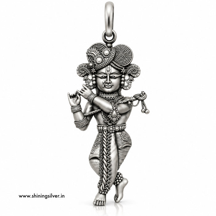 An intricate sterling silver pendant of a dancing Hindu deity, likely Lord Krishna, featuring detailed engravings, textured patterns, and a decorative headdress, shown on a plain white background with a website watermark.