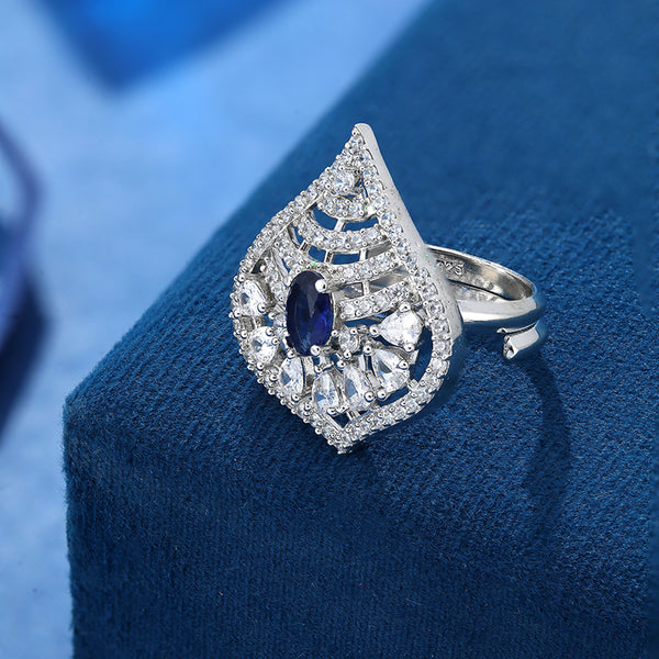 Cocktail design 925 Sterling Silver Ring For Women studded with American diamonds and sapphires placed on a blue display base