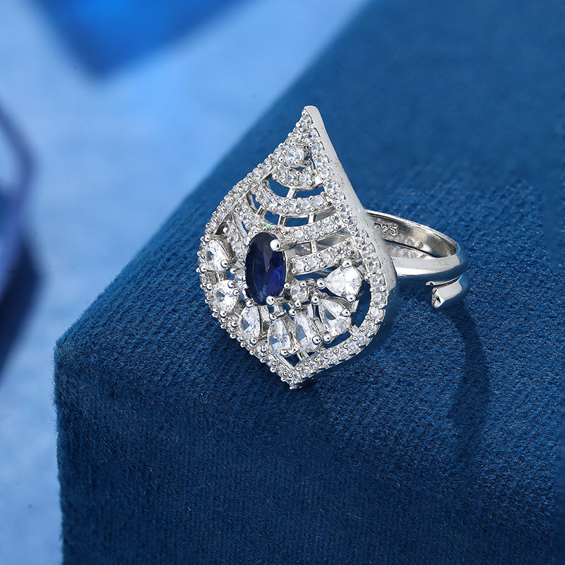 Cocktail design 925 Sterling Silver Ring For Women studded with American diamonds and sapphires placed on a blue display base
