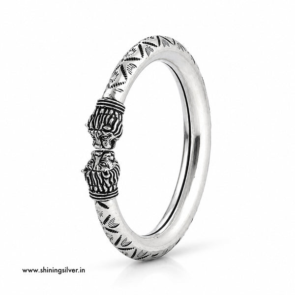 A sterling silver band ring with detailed lion head carvings and geometric patterns on the band, shown on a clean white background.