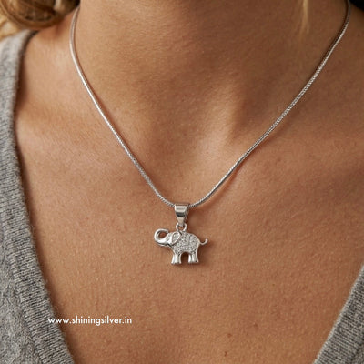 Silver elephant pendant necklace on a person's neck with 'www.shiningsilver.in' branding.