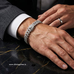 Close-up of a hand wearing a silver bracelet on a dark marble surface.