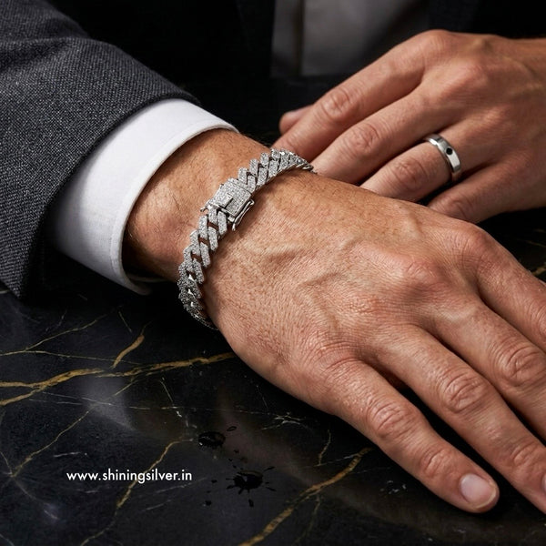 Close-up of a hand wearing a silver bracelet on a dark marble surface.