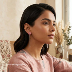 Woman wearing pink earrings in a home setting with 'www.shiningsilver.in' branding.