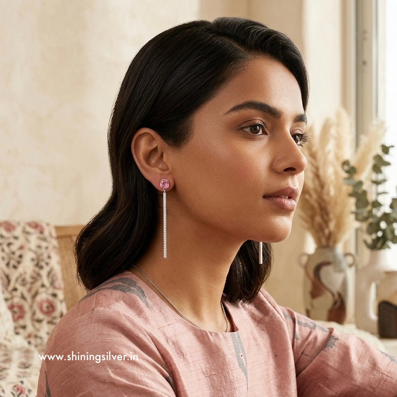 Woman wearing pink earrings in a home setting with 'www.shiningsilver.in' branding.