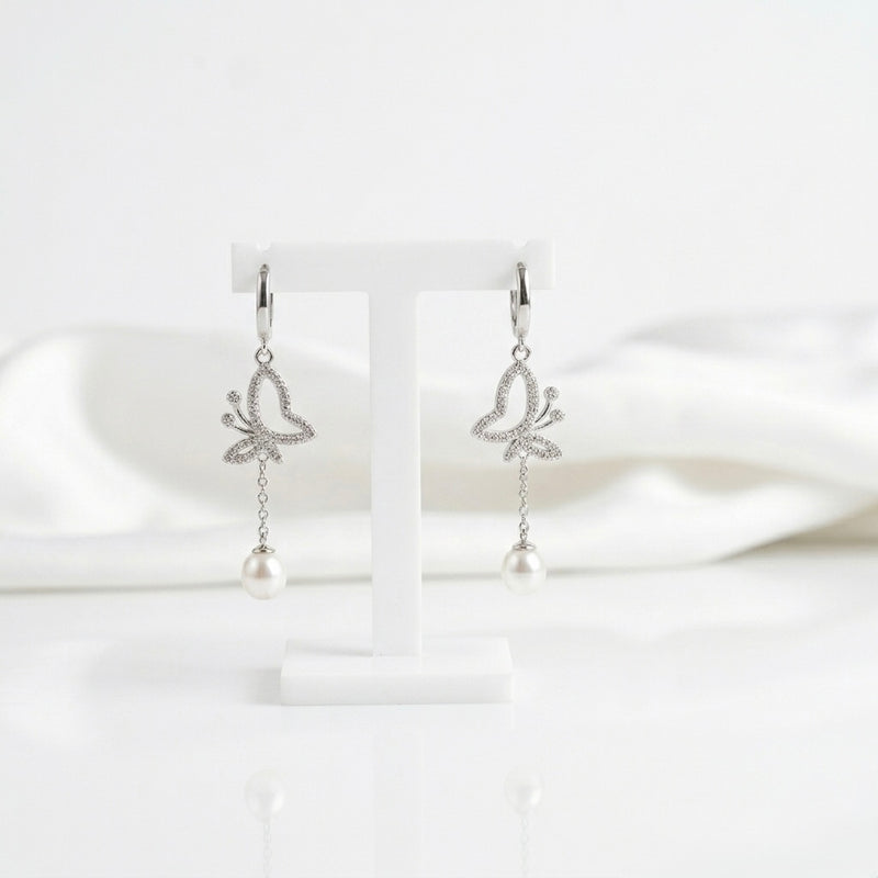 Butterfly-shaped earrings with pearl drops on a white background “shiningsilver.in”