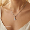 Silver butterfly necklace on a person's neck with a neutral background, shining silver