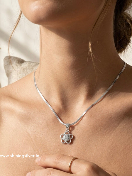 Silver necklace with a pendant worn by a person, with a blurred background. Shiningsilver.in