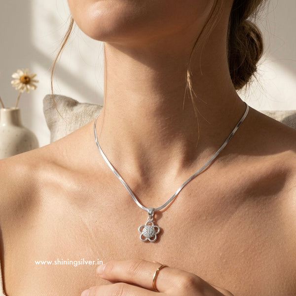 Silver necklace with a pendant worn by a person, with a blurred background. Shiningsilver.in