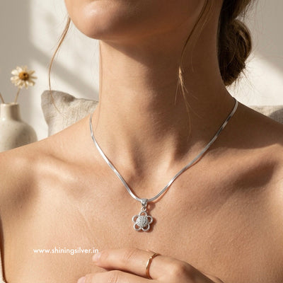 Silver necklace with a pendant worn by a person, with a blurred background. Shiningsilver.in