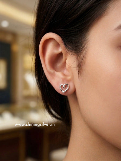 Heart-shaped earring worn by a person with a blurred background. shininsilver.in