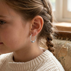 Close-up of a girl wearing a silver hoop earring with a blurred background