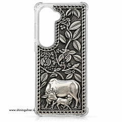 A clear smartphone case with a highly detailed embossed silver-toned design featuring a cow and calf under leafy branches, shown on a white background.