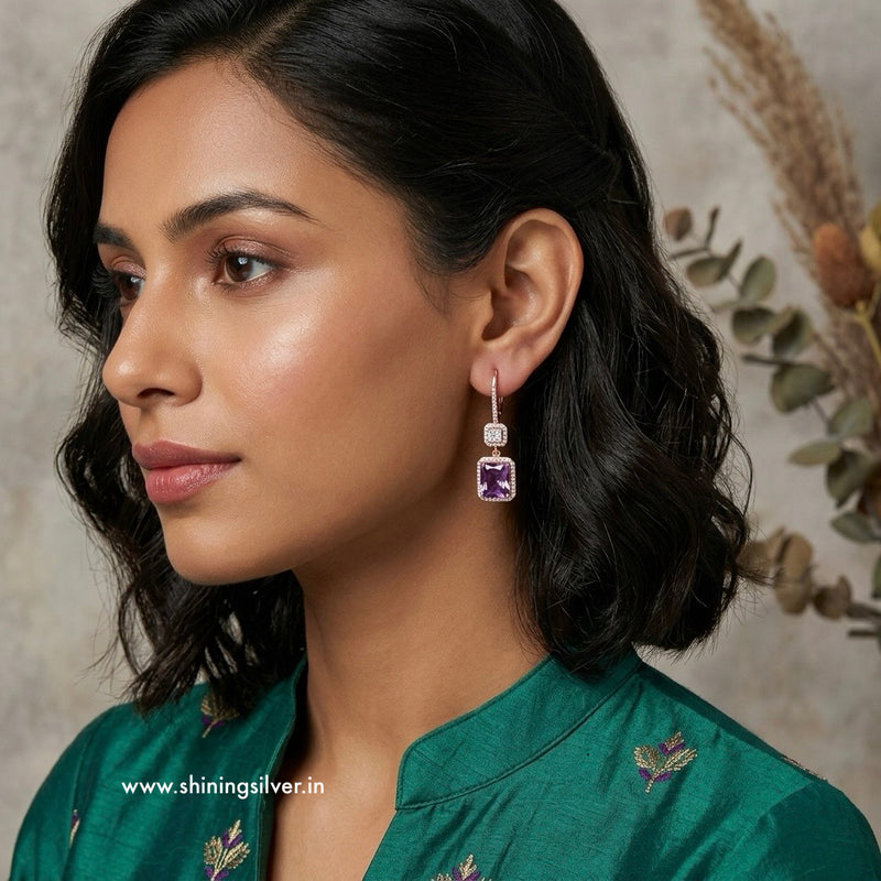 Woman wearing a pair of earrings with a visible shiningsilver.in brand name.