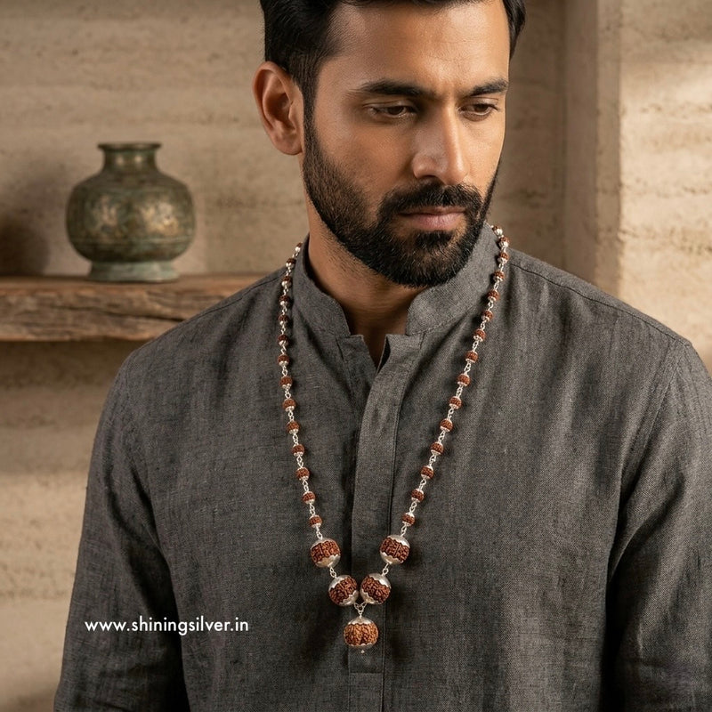 Man wearing a long necklace with a neutral background shining silver original rudraksh