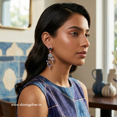 Woman wearing chandelier earrings in a room with decorative elements