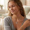 Woman wearing a silver necklace with an elephant pendant in a cozy indoor setting. Shining silver