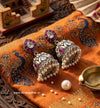 Silver earrings with pearls and red stones on a decorative fabric background