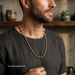 Man wearing a rudraksh necklace with a rustic background