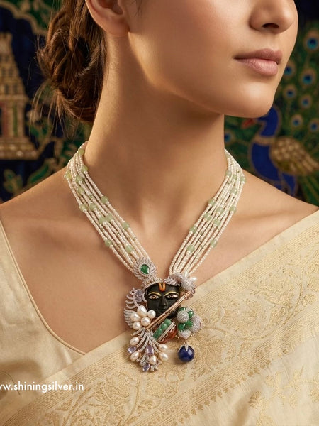 Woman wearing a detailed shrinath ji necklace with a decorative background “shiningsilver.in”