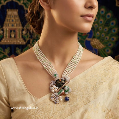 Woman wearing a detailed shrinath ji necklace with a decorative background “shiningsilver.in”