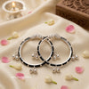 A pair of traditional Indian silver baby kadas featuring protective black beads, an intricate silver centerpiece, and hanging ghungroo bells.